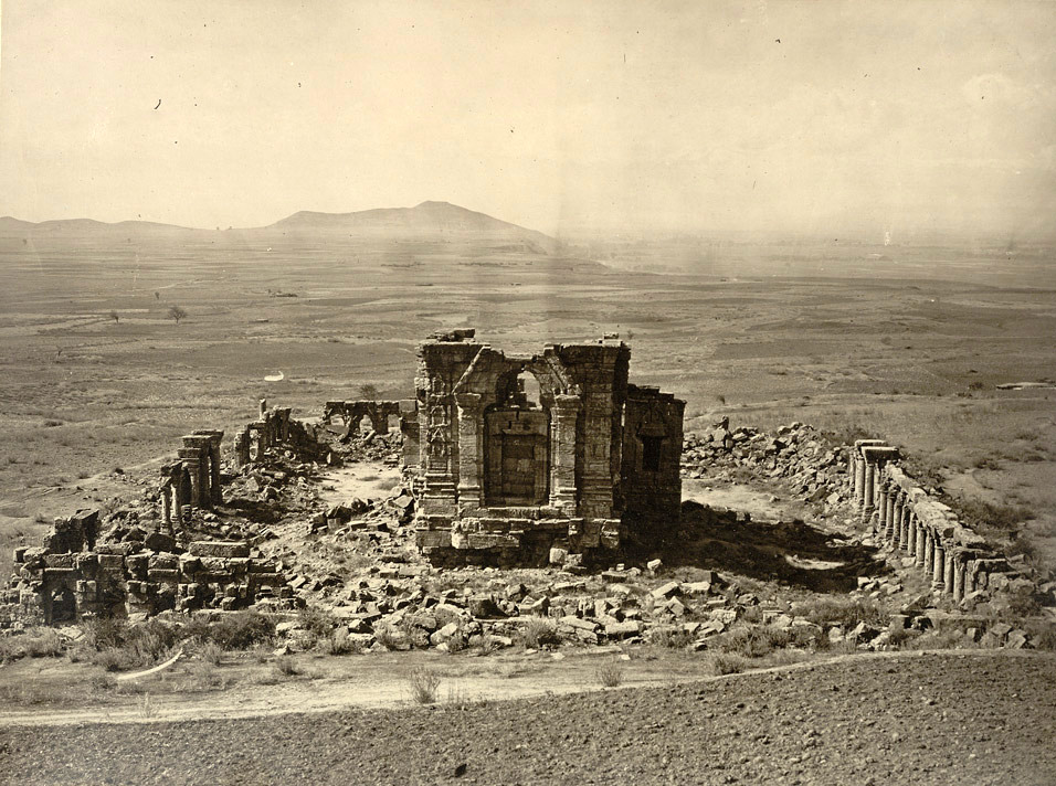 Kashmir. General view of Temple and Enclosure of Marttand or the Sun, near Bhawan. Probable date of temple A.D. 490-555. Probable date of colonnade A.D. 693-729 Photograph of the Surya Temple at Martand in Jammu & Kashmir taken by John Burke in 1868. This general view from the hillside looking down onto the ruins of the temple was reproduced in Henry Hardy Cole's Archaeological Survey of India Report 'Illustrations of Ancient Buildings in Kashmir.' (1869). Cole stated, 'The most impressive and grandest ruins in Kashmir, are at Marttand, which is about three miles east of Anantnag.' . The Surya temple is situated on a high plateau and commands superb views over the Kashmir valley. Dedicated to the sun god, it is considered a masterpiece of early temple architecture in Kashmir. It was built by Lalitaditya Muktapida (ruled c.724-c.760) of the Karkota dynasty, one of the greatest of Kashmir's rulers, under whom both Buddhism and Hinduism flourished. The temple consists of a principal sanctuary standing on a high plinth in a rectangular colonnaded court, surrounded by 84 small shrines. Its roof has disappeared but the immense doorway before the sanctum still stands, consisting of a trefoil arch set within a tall triangular pediment standing on engaged pilasters.
